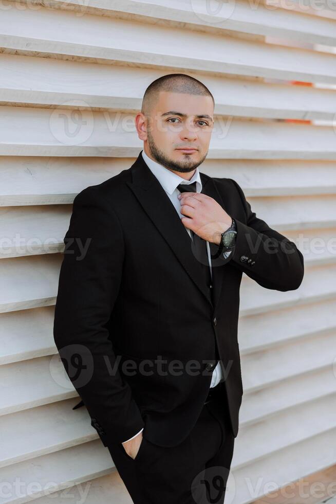 Portrait of a handsome young groom on an autumn day outdoors in an elegant suit. Outdoor photo. Handsome man in a business suit. photo