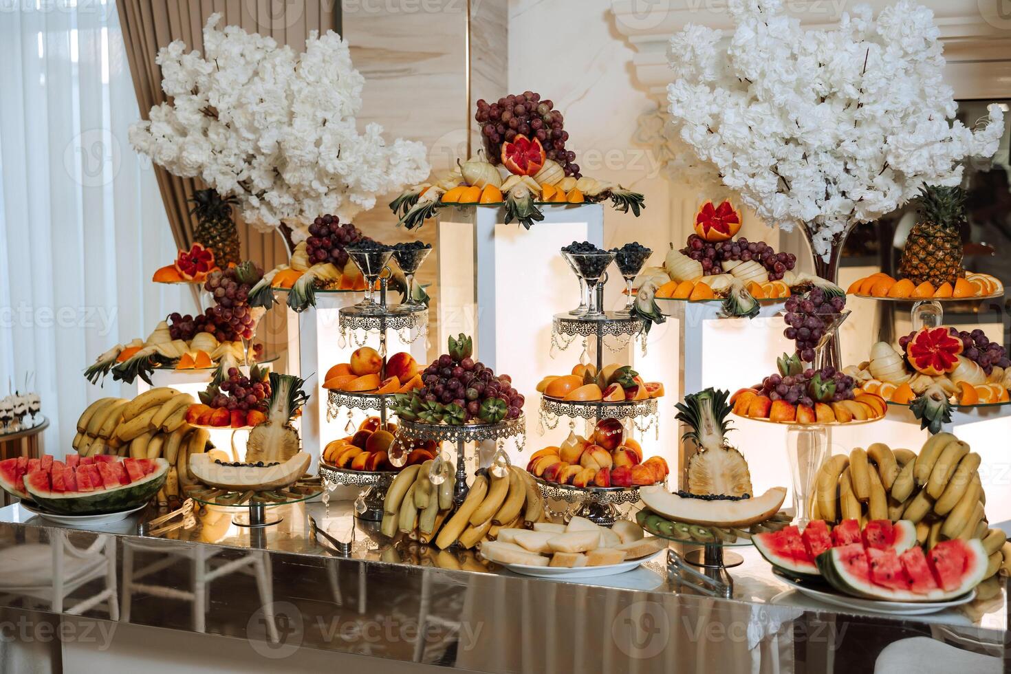A banquet table full of fruits and berries, an assortment of sweets. Bananas, grapes, pineapples. Fruit compositions for the holiday. photo