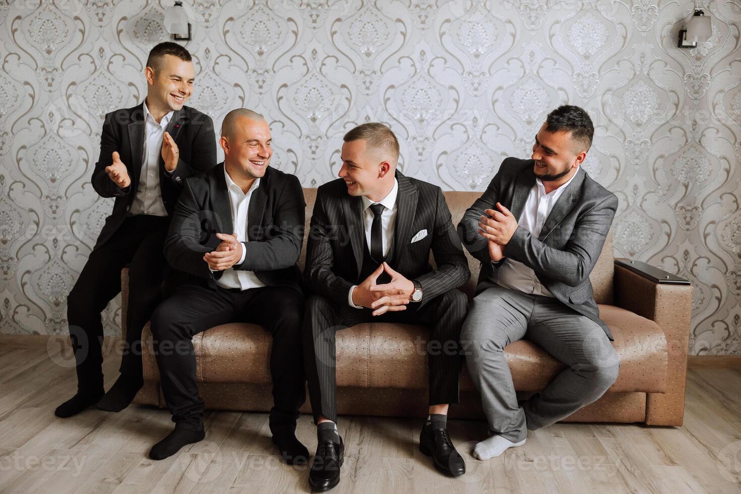 A young groom and his funny friends pose for the camera. A group of young people hug the groom and cheerfully congratulate him. Happy friends. Friends in the room. Wedding day. photo