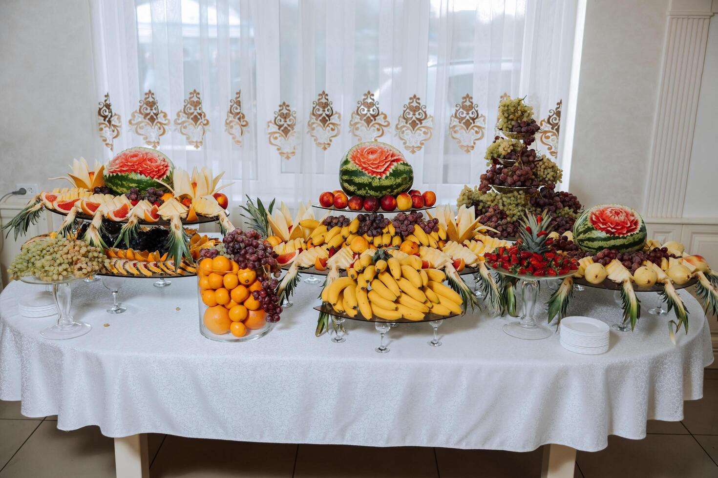 un banquete mesa lleno de frutas y bayas, un surtido de dulces plátanos, uvas, piñas. Fruta composiciones para el día festivo. foto