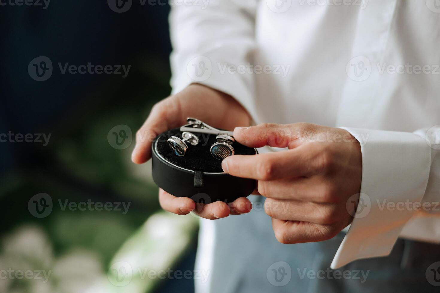 The man put on his shirt and straightens cufflinks. The groom fasten cufflinks on the cuffs of the shirt. The businessman fasten cufflinks on the cuffs of the shirt. Concept successful businessman. photo