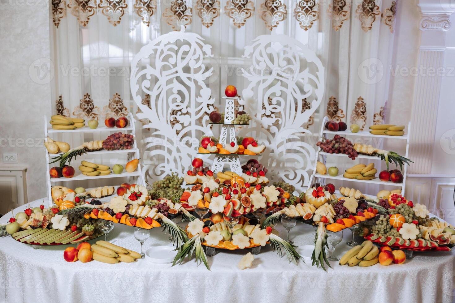 A banquet table full of fruits and berries, an assortment of sweets. Bananas, grapes, pineapples. Fruit compositions for the holiday. photo