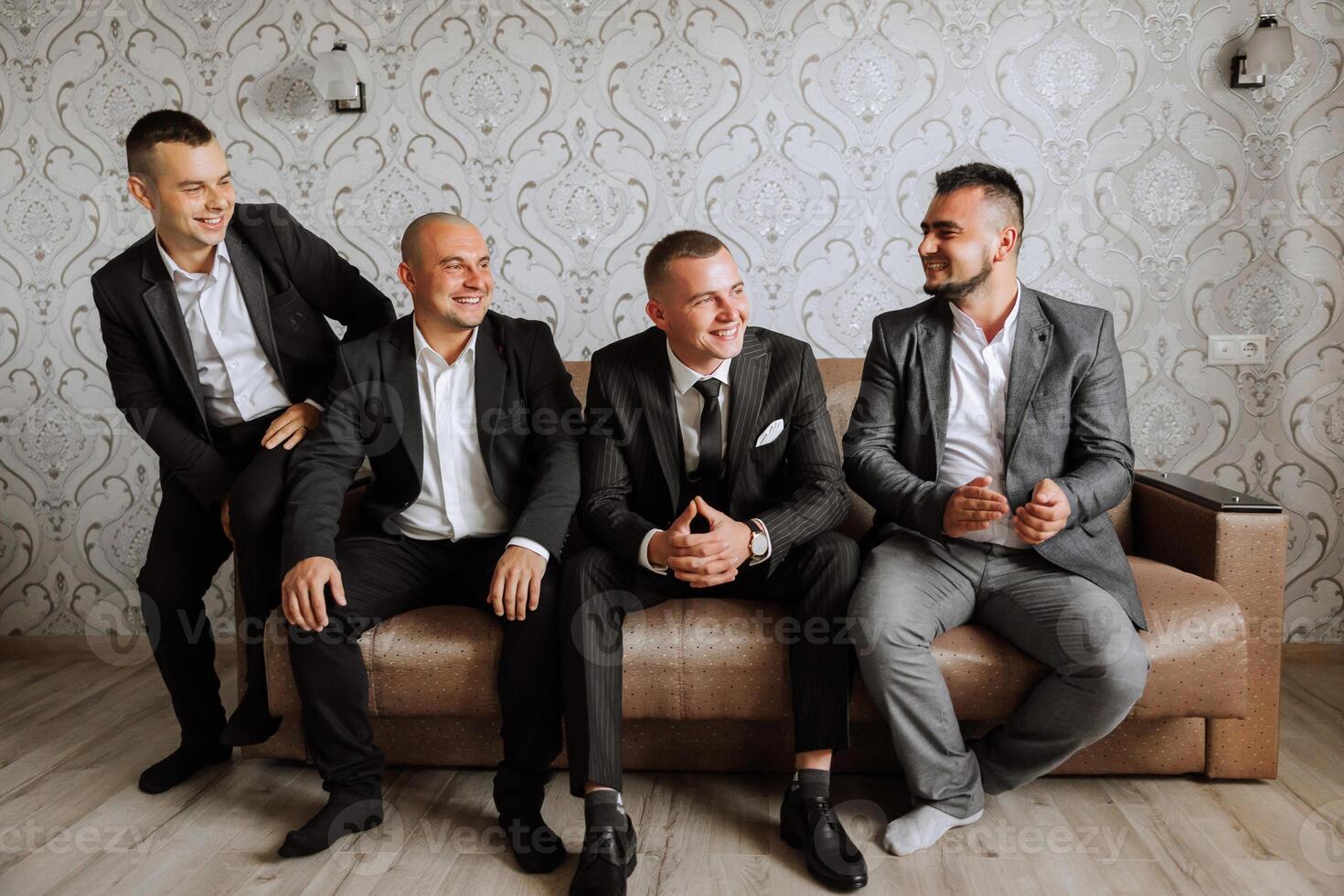 A young groom and his funny friends pose for the camera. A group of young people hug the groom and cheerfully congratulate him. Happy friends. Friends in the room. Wedding day. photo