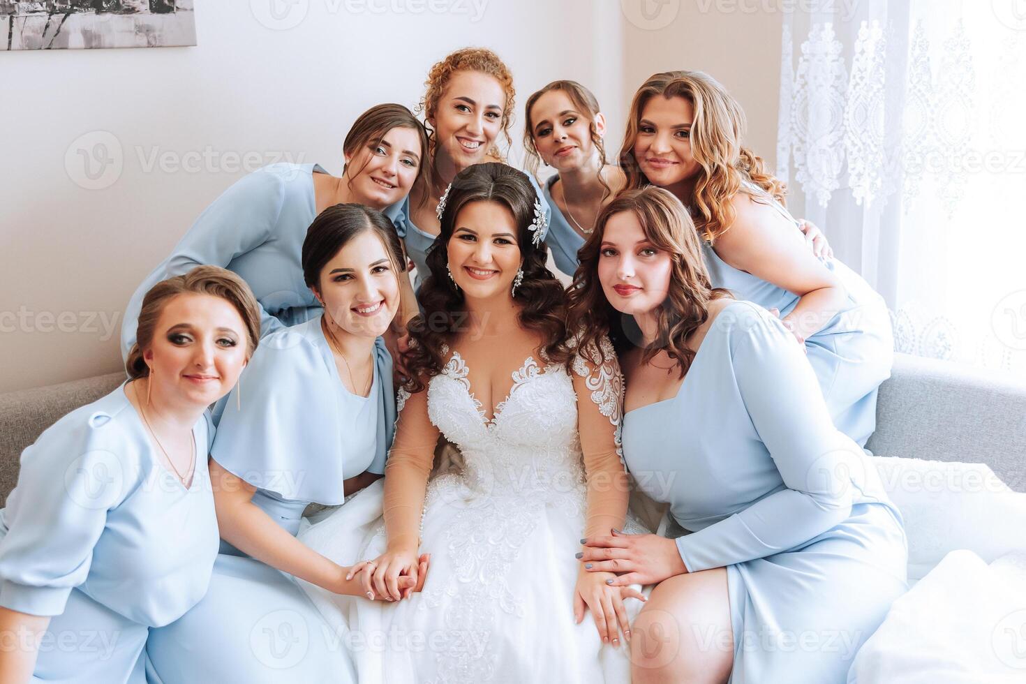 Portrait of the bride with her friends. Elegant and stylish bride with her friends in matching dresses in the room in the morning. Many beautiful girls in one photo. photo
