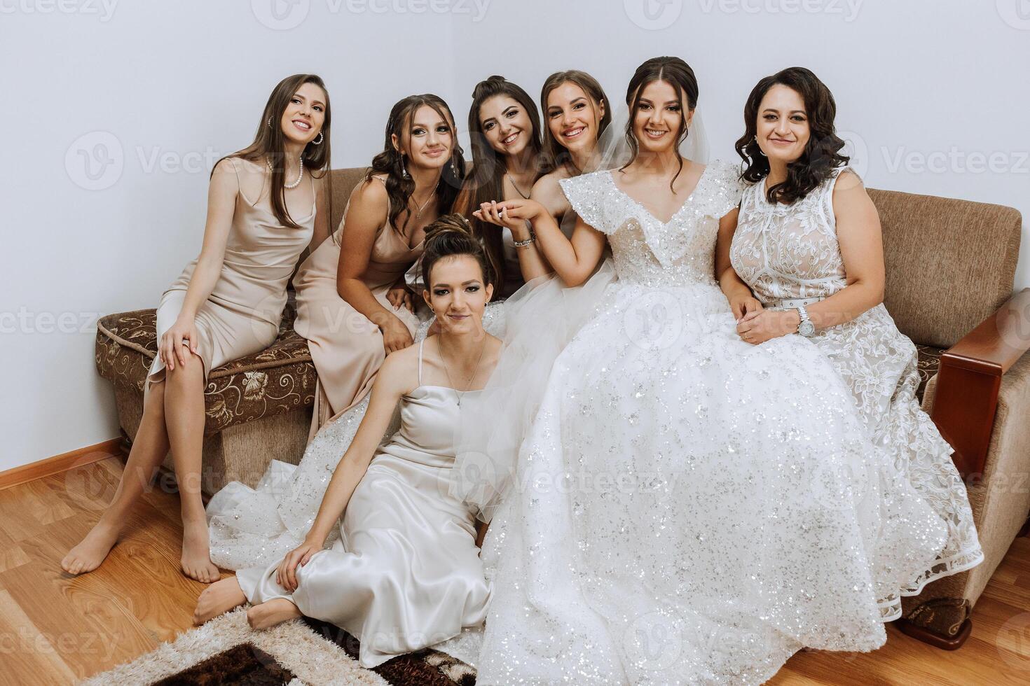 retrato de el novia con su amigos. elegante y elegante novia con su amigos en pareo vestidos en el habitación en el Mañana. muchos hermosa muchachas en uno foto. foto