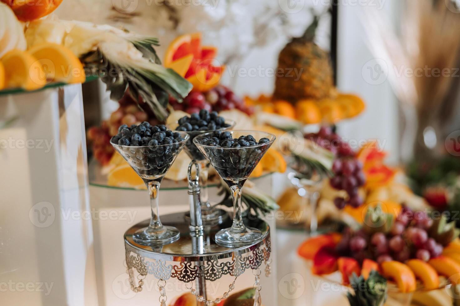 A banquet table full of fruits and berries, an assortment of sweets. Bananas, grapes, pineapples. Fruit compositions for the holiday. photo