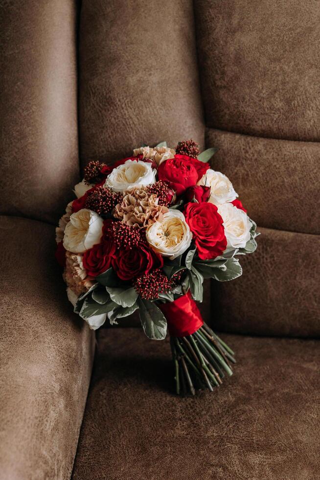 Wedding bouquet. Freshly cut roses, green seed heads and leaves. Green stems, white ribbon and gold wedding rings. The concept of a wedding bouquet. photo