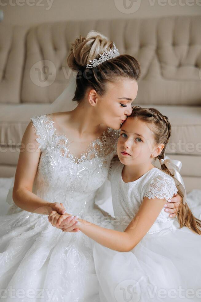 Portrait of the bride with her little sister in the room. Tender and sweet photo of a beautiful bride with her little sister.