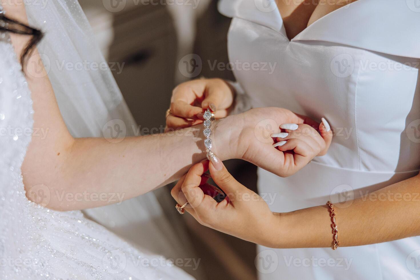 Wedding bride and bridesmaid help with jewellery bracelet for elegant and classic fashion glamour. Expensive bridal diamond accessory for classy style at special ceremony event day closeup. photo