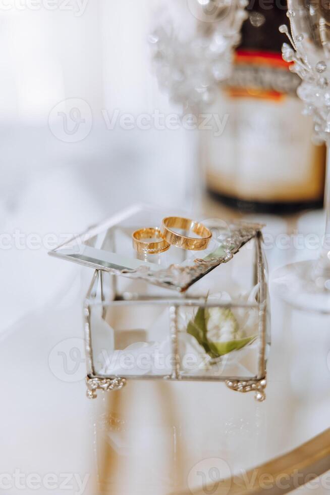 Wedding details. Gold wedding rings on a glass box with a silver frame photo