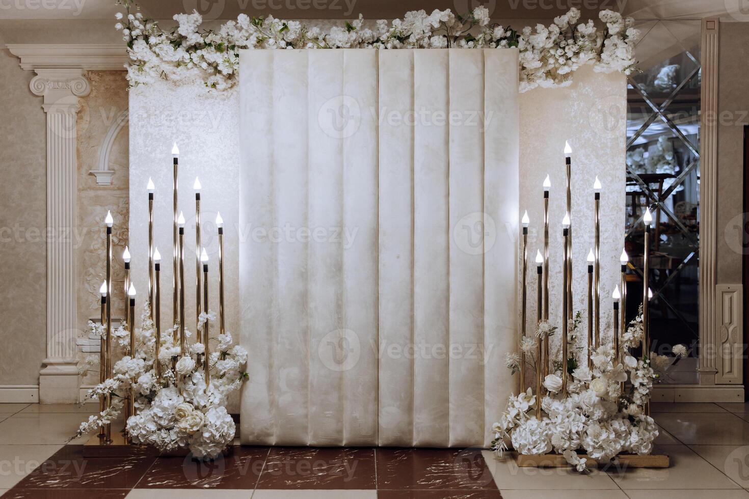 The photo zone at a wedding or birthday celebration is decorated with flowers and illuminated by artificial light
