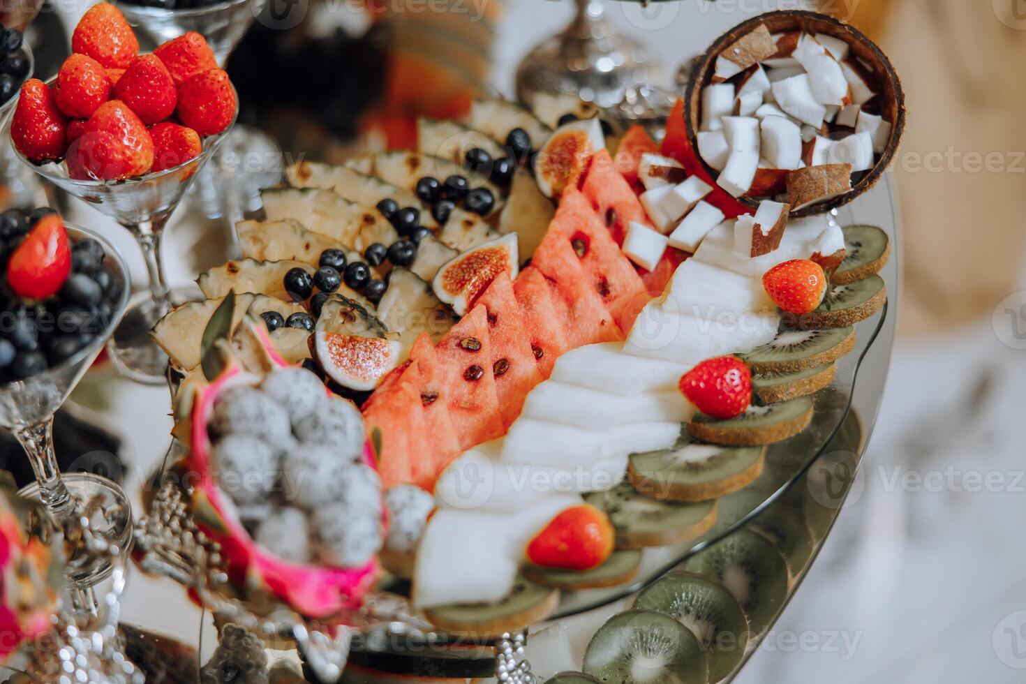 A banquet table full of fruits and berries, an assortment of sweets. Bananas, grapes, pineapples. Fruit compositions for the holiday. photo