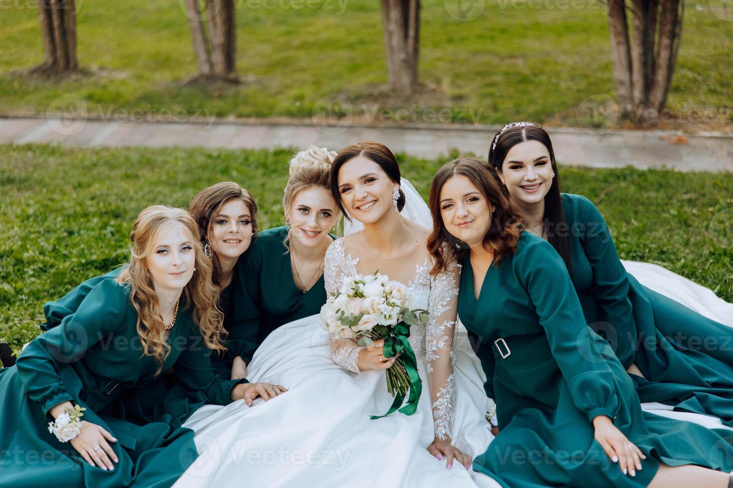 Wedding photography. A brunette bride in a wedding dress and her friends in emerald dresses photo