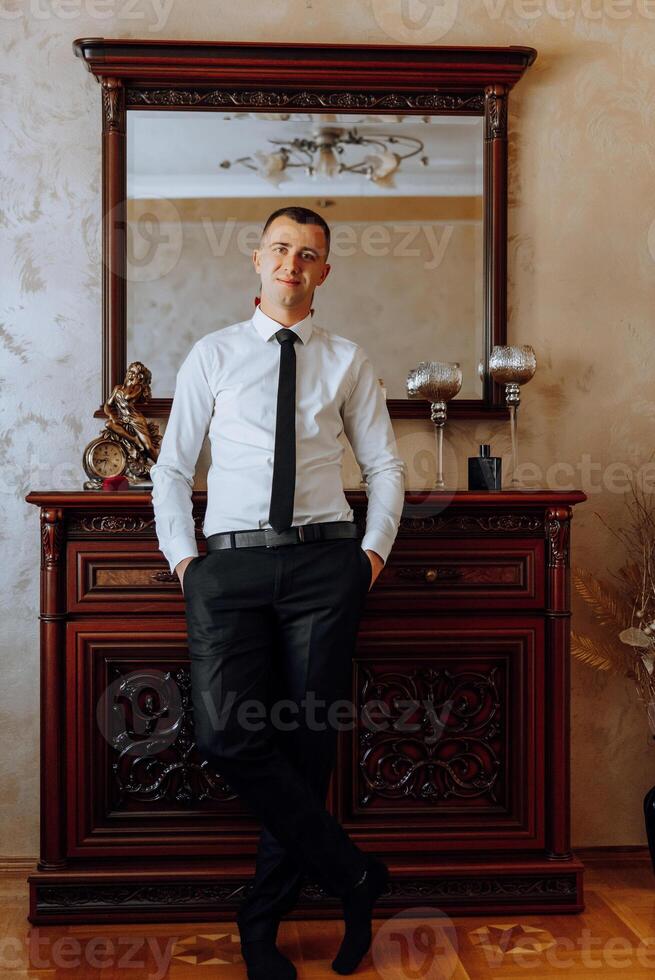 Portrait of smiling successful Caucasian man in formal suit, posing in room, happy young male boss or CEO looking at camera, showing confidence and strength, leadership concept photo