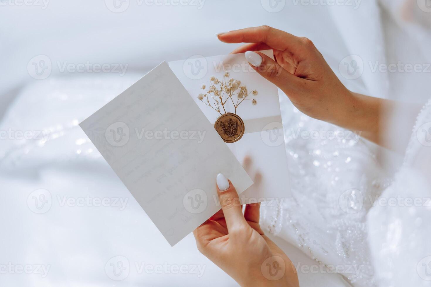 The bride in her hands holds a white envelope, an invitation, a gift sheet of paper. Close-up wedding photography, copy space, portrait. photo