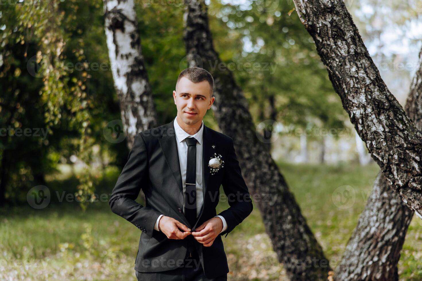 Portrait of a handsome young groom on an autumn day outdoors in an elegant suit. Outdoor photo. Handsome man in a business suit. photo