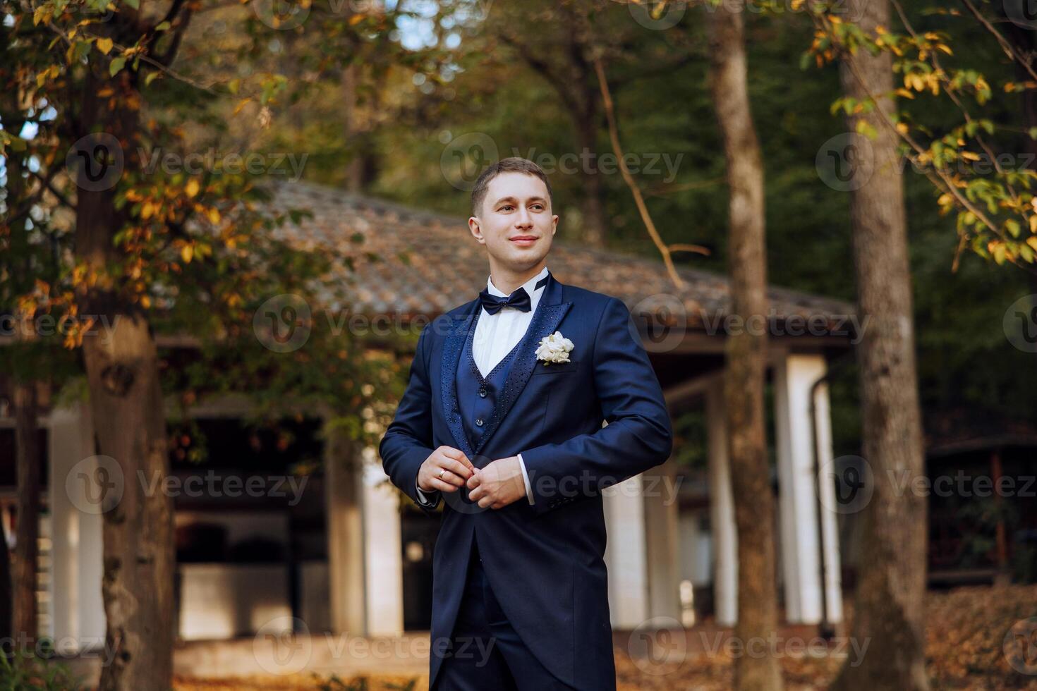 Portrait of a handsome young groom on an autumn day outdoors in an elegant suit. Outdoor photo. Handsome man in a business suit. photo