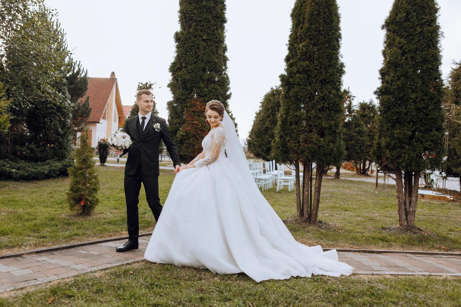 un Boda Pareja es caminando en naturaleza en un otoño día. contento joven novia y elegante novio participación manos. un elegante Pareja de recién casados en su Boda día. foto