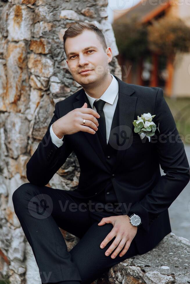Portrait of a handsome young groom on an autumn day outdoors in an elegant suit. Outdoor photo. Handsome man in a business suit. photo