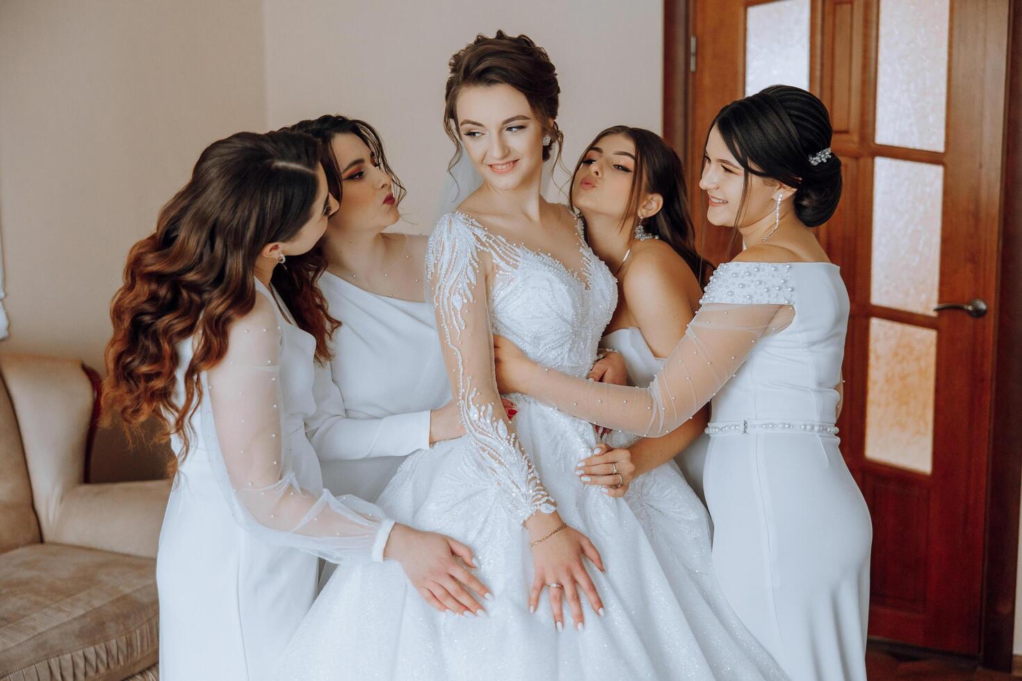 Portrait of the bride with her friends. Elegant and stylish bride with her friends in matching dresses in the room in the morning. Many beautiful girls in one photo. photo