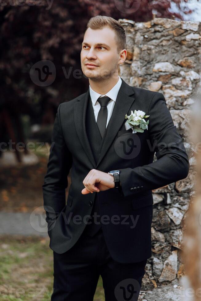 Portrait of a handsome young groom on an autumn day outdoors in an elegant suit. Outdoor photo. Handsome man in a business suit. photo