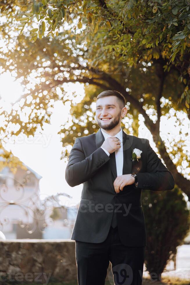 Portrait of a handsome young groom on an autumn day outdoors in an elegant suit. Outdoor photo. Handsome man in a business suit. photo