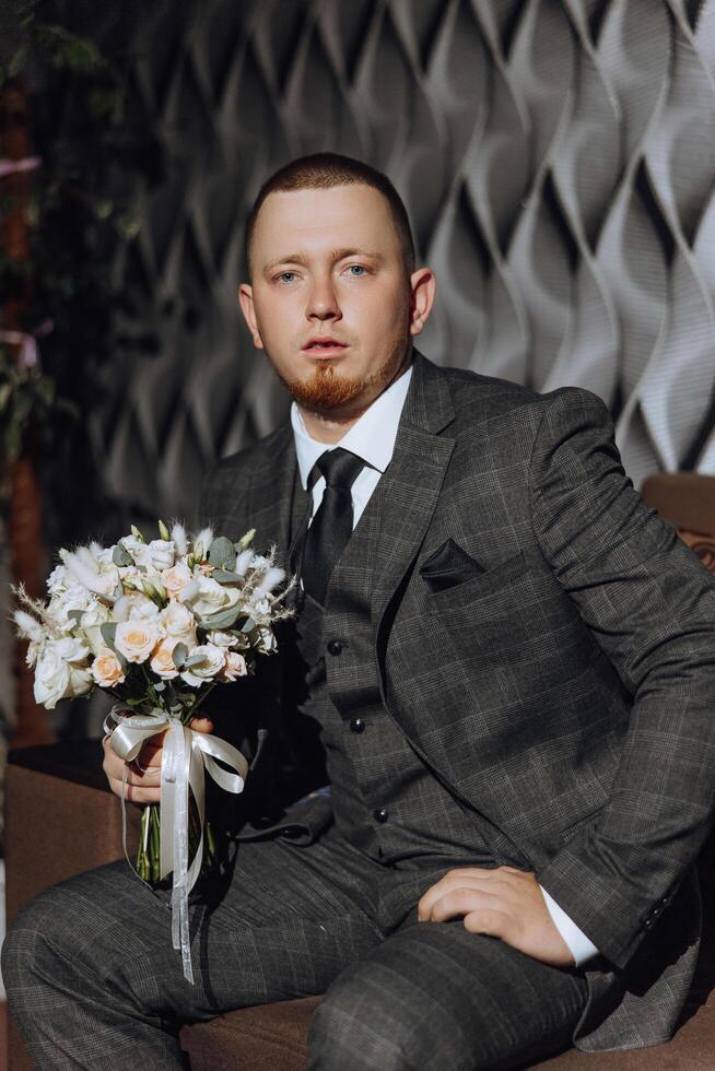 groom with a bouquet of roses, groom with bouquet, groom with a wedding bouquet, a young man with a wedding bouquet on his hand, well suited man photo