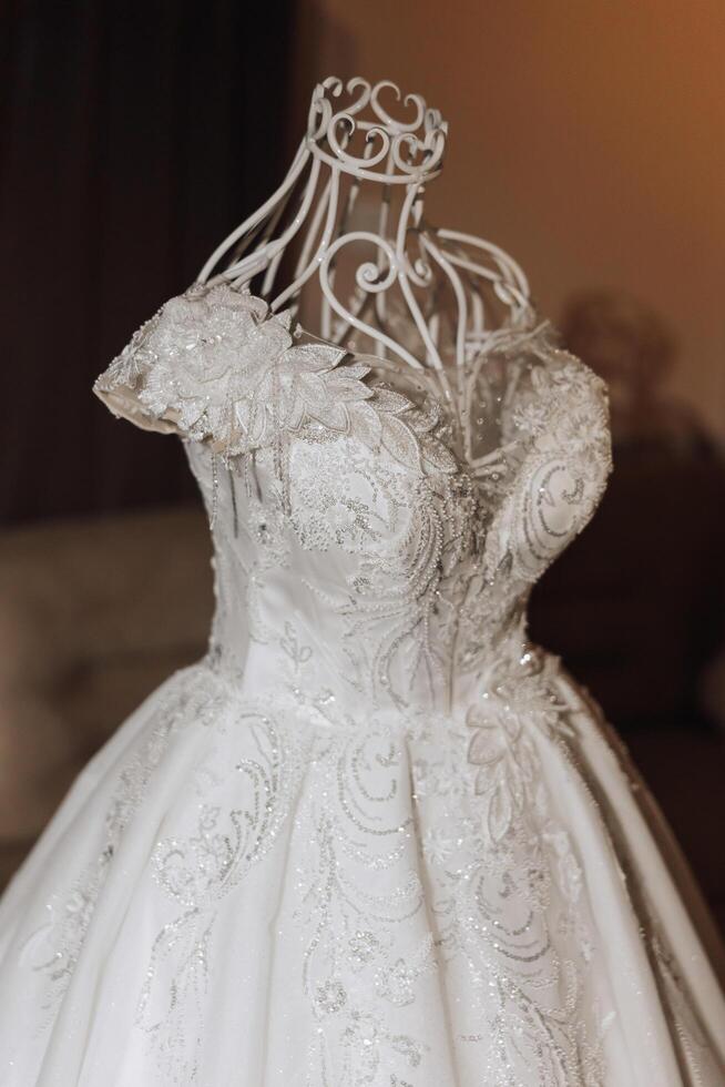 Bedroom interior with wedding dress prepared for the ceremony. A beautiful lush wedding dress on a mannequin in a hotel room. photo