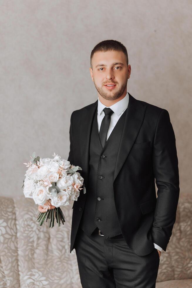 groom with a bouquet of roses, groom with bouquet, groom with a wedding bouquet, a young man with a wedding bouquet on his hand, well suited man photo