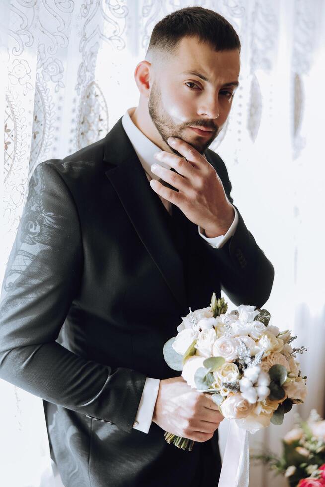 groom with a bouquet of roses, groom with bouquet, groom with a wedding bouquet, a young man with a wedding bouquet on his hand, well suited man photo