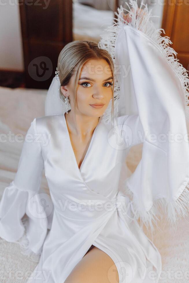 Closeup blond bride with fashion wedding hairstyle and makeup. A youthful bride with a sophisticated bridal hairdo indoors by a window photo