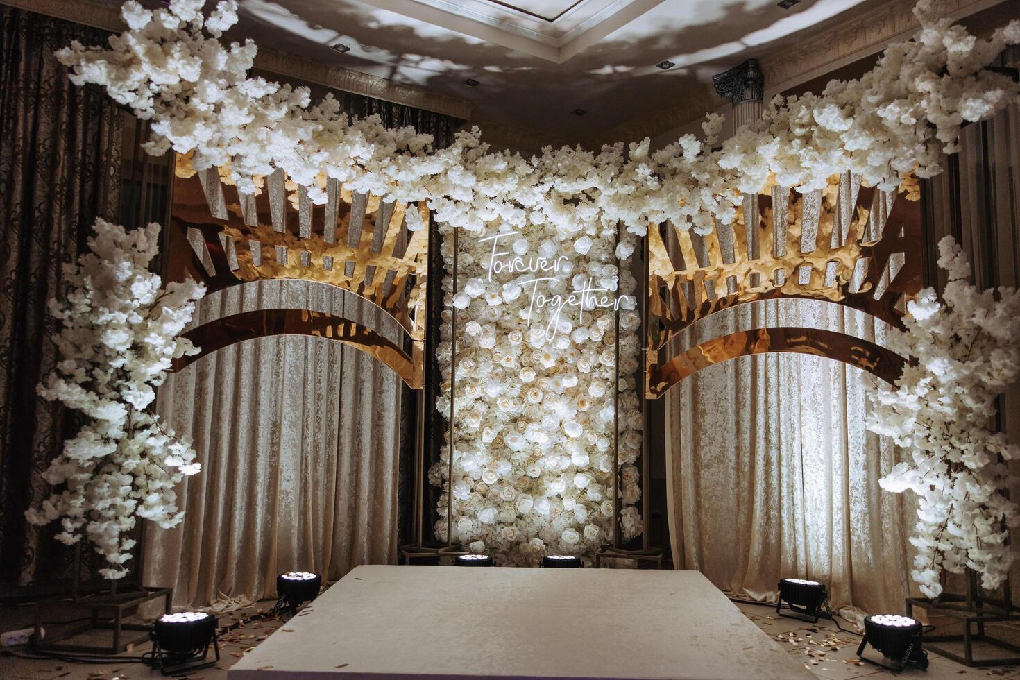 The photo zone at a wedding or birthday celebration is decorated with flowers and illuminated by artificial light
