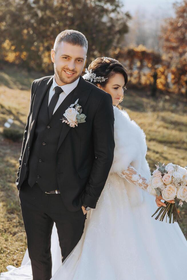 Wedding couple on a walk in the autumn park. The bride in a beautiful white dress. Love and relationship concept. Groom and bride in nature outdoors photo