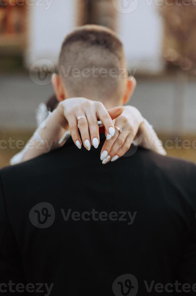 Brides hand arm around groom. Wedding day moment. Bride holding grooms shoulder, in love couple on wedding day together. Bride and groom. flowers and rings. Brides hand holding groom. photo