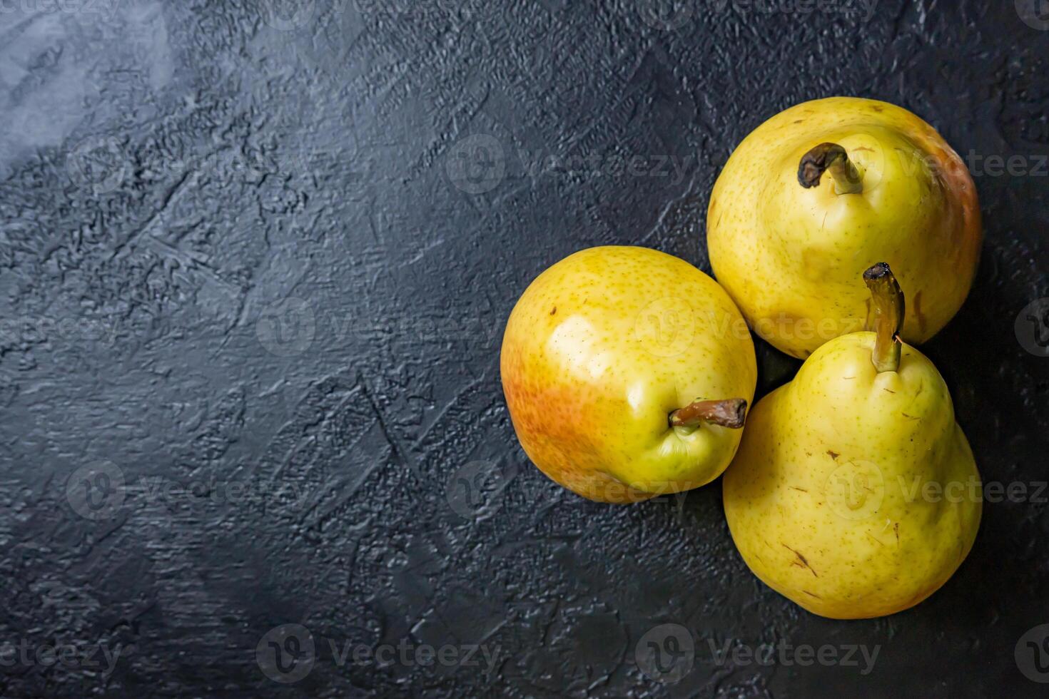 Fresh fruit on dark background. Composition of three pears. photo