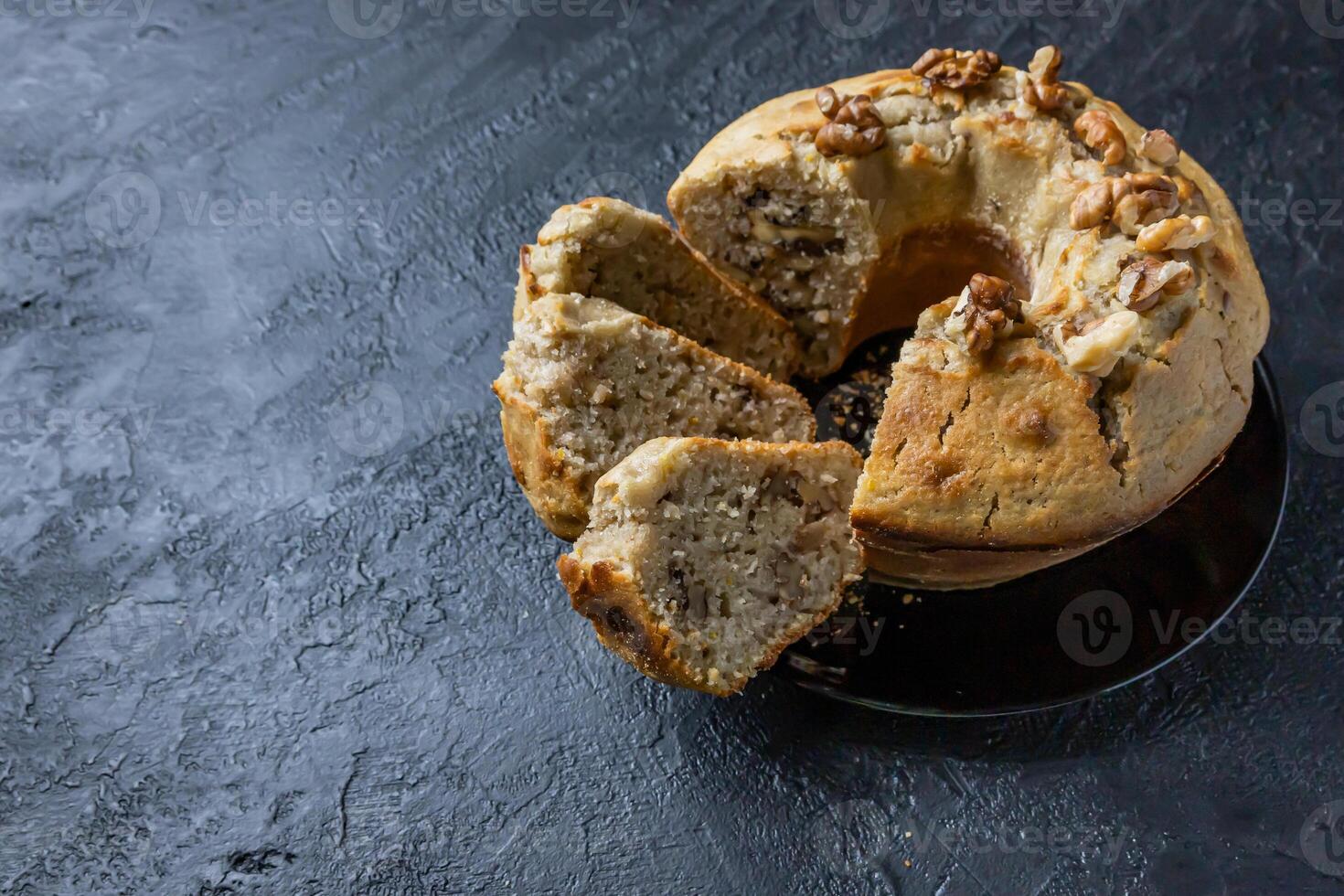 Nut Cake. Composition of a cake on a plate with three slices on a dark table. photo