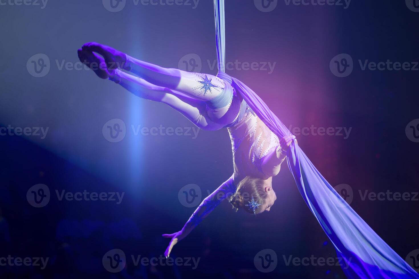 Performance by a circus acrobat artist. Girls perform aerial acrobatic elements on fabric. photo