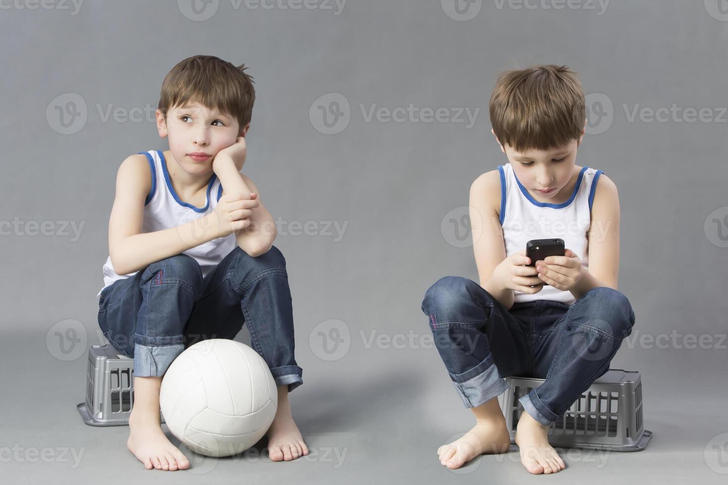 Two brothers twin with different characters. A boy with a soccer ball and his friend with a mobile phone. photo
