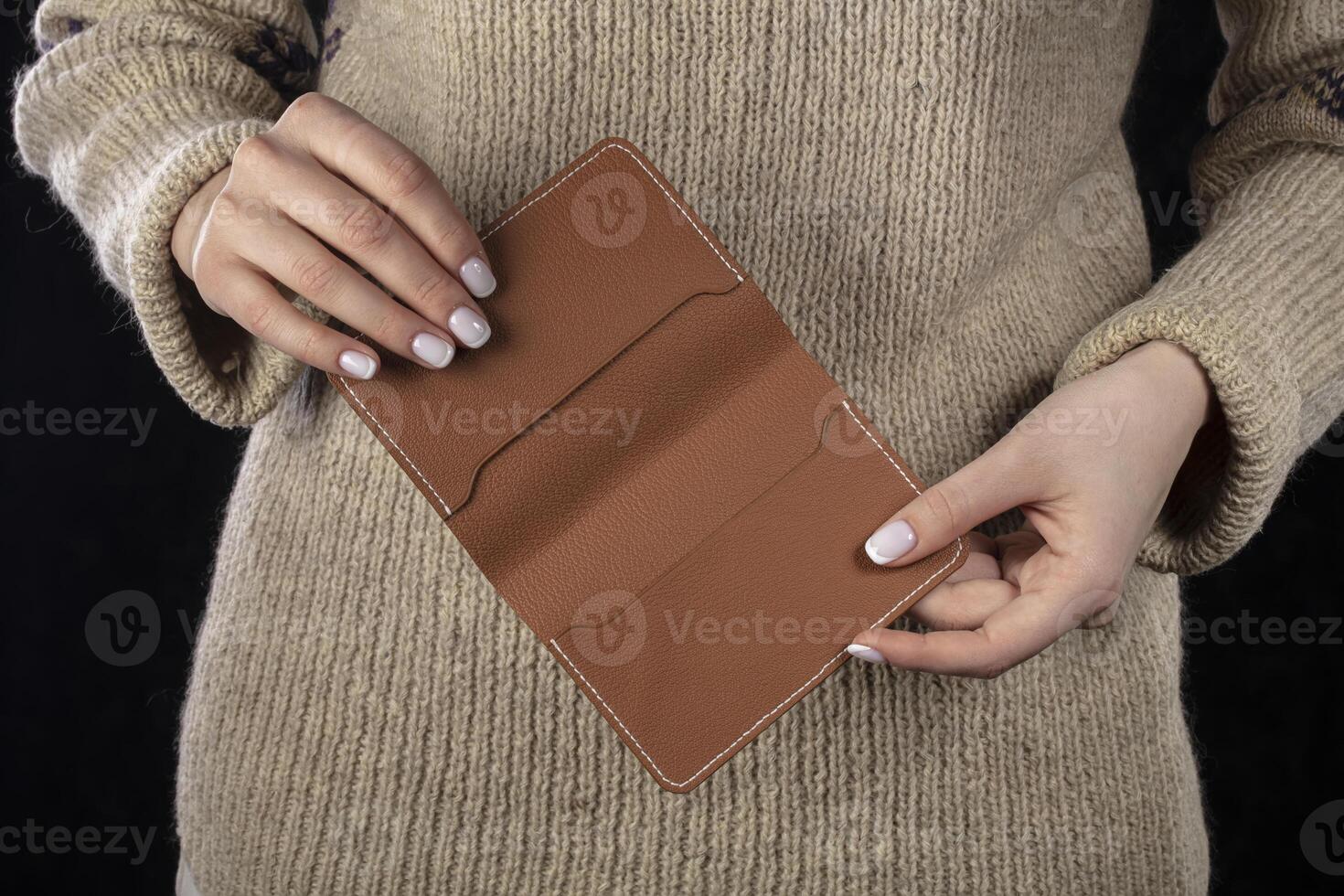 A brown leather wallet is in women's hands. photo