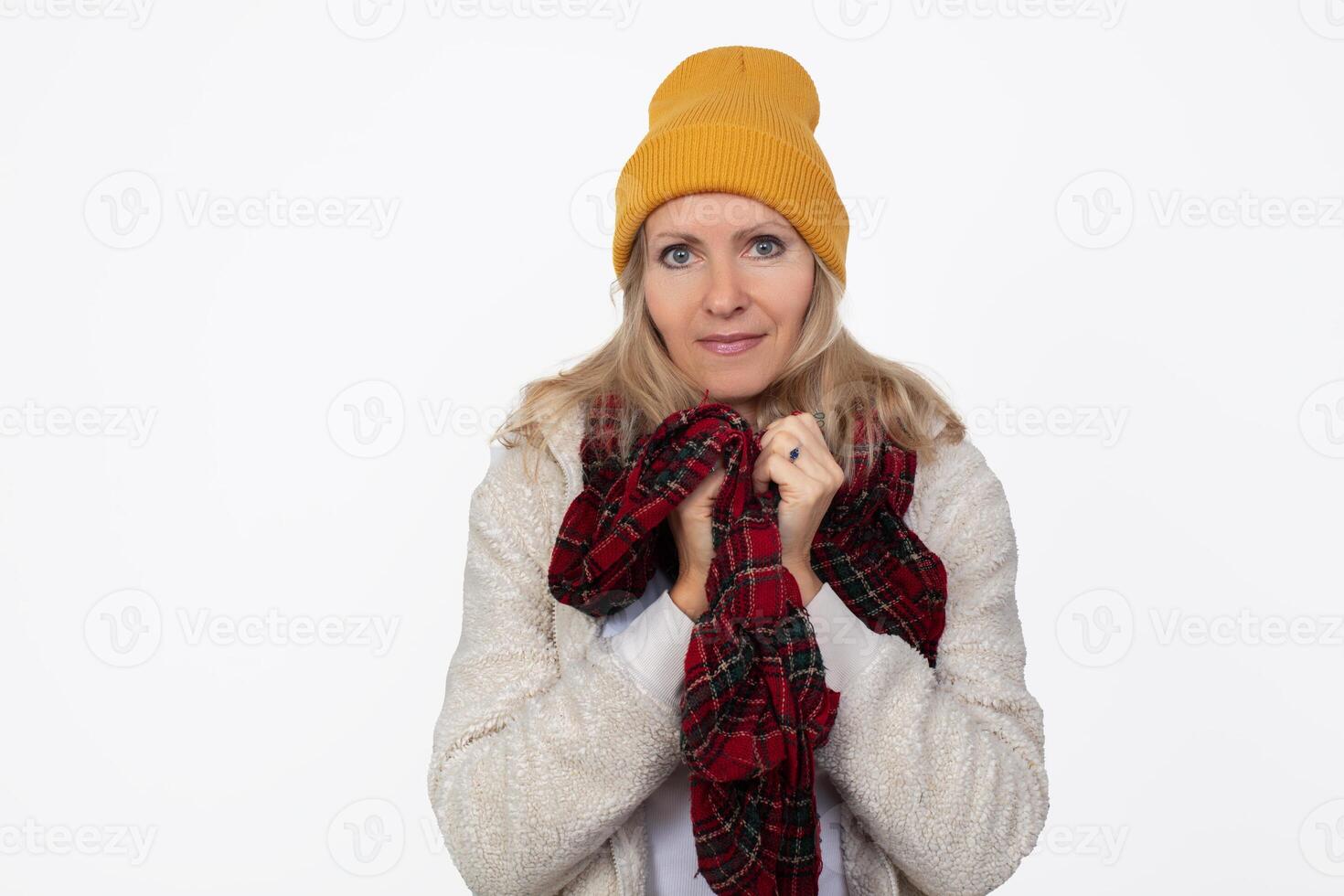 A beautiful adult woman in a knitted hat and scarf smiles and looks at the camera. photo