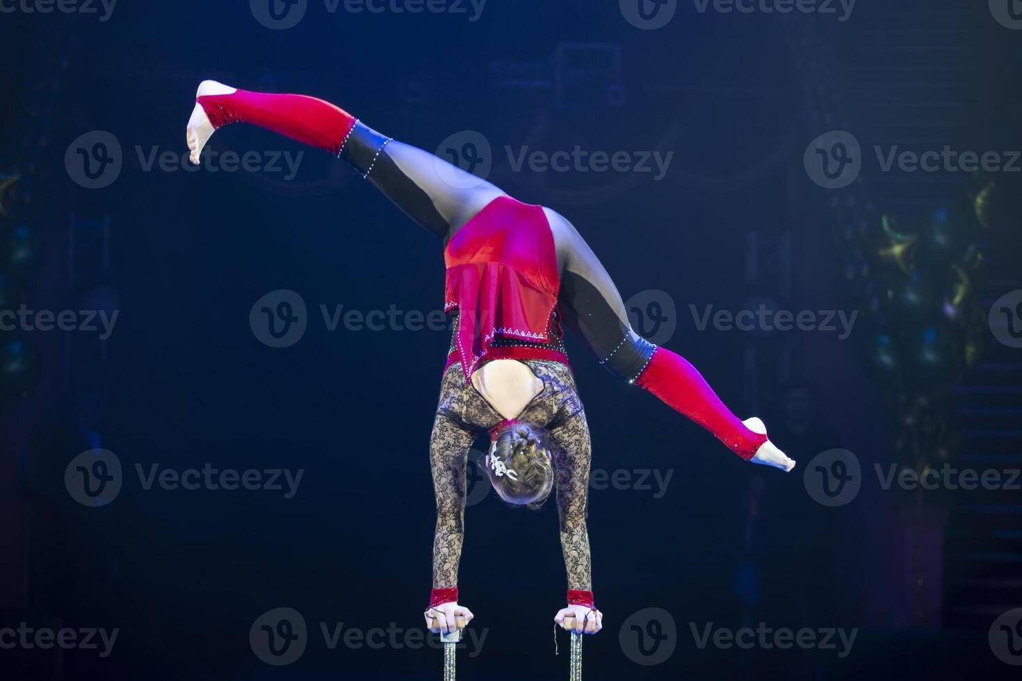 A gymnast performs in a show. A girl gymnast performs a circus acrobatic performance. photo