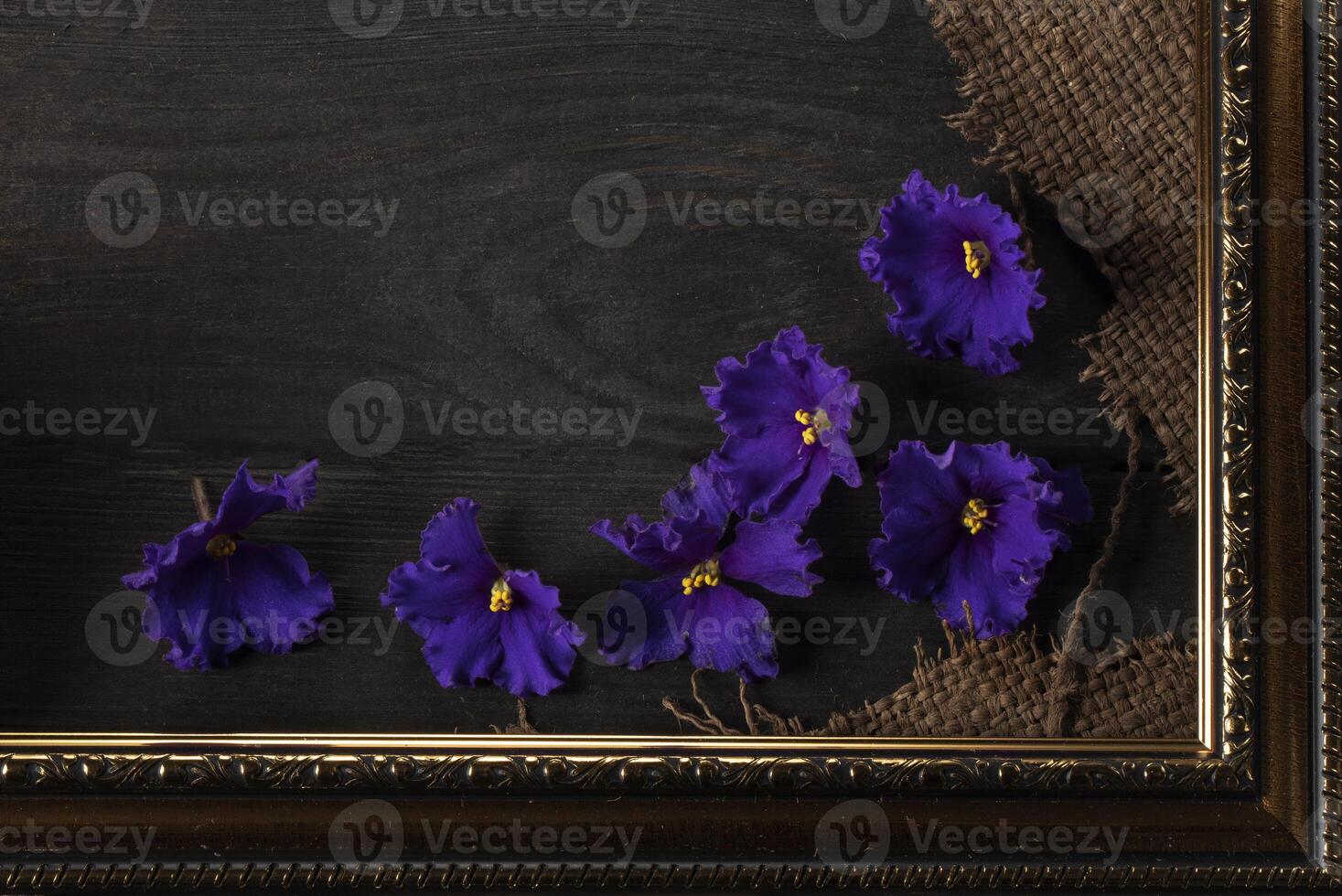 Part of a beautiful frame contains rough weave fabric on a wooden background and violet flowers. Background for the inscription. photo