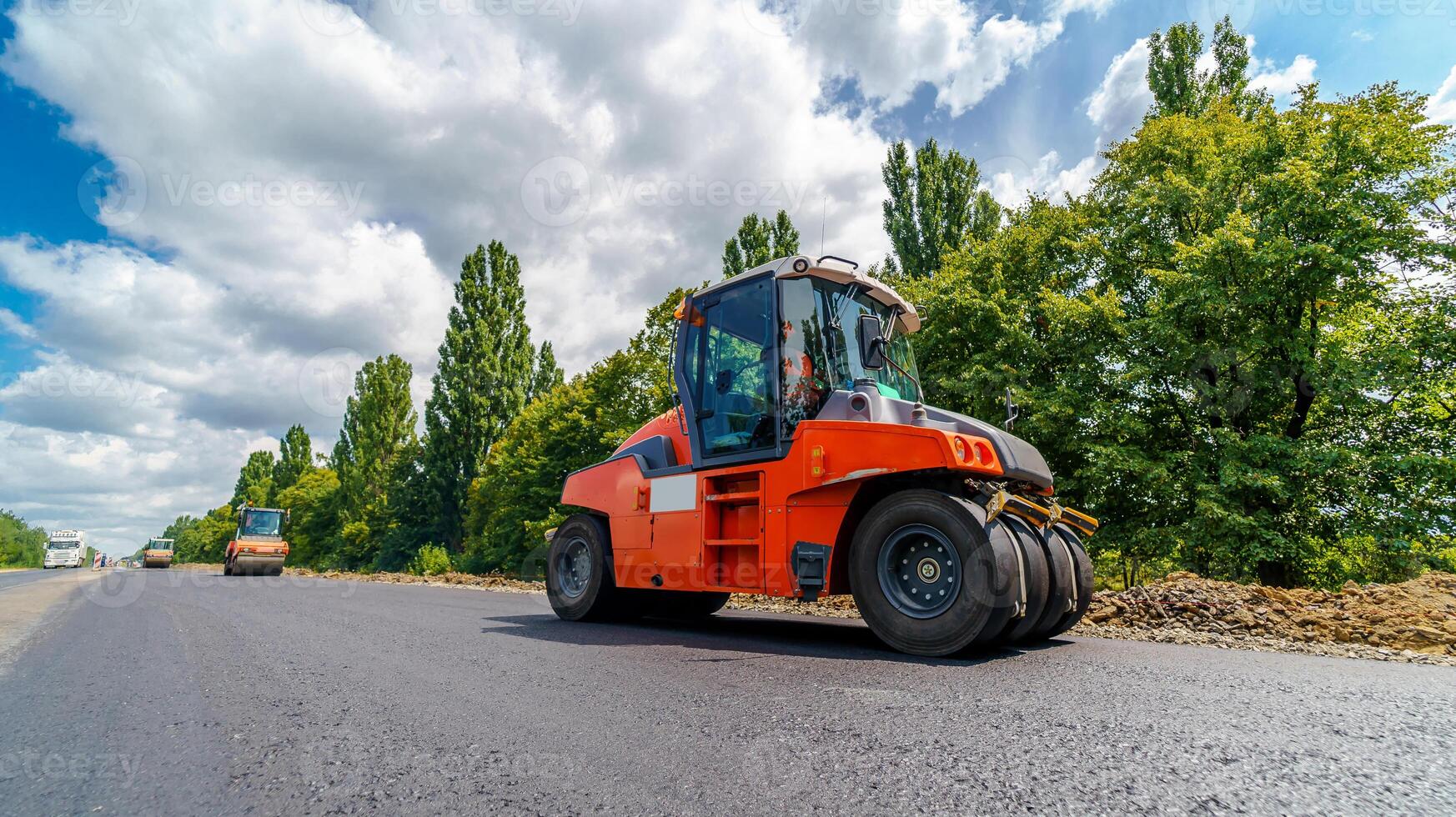 Road repair, roller flattening new asphalt. Heavy special machines. Asphalt paver in operation. Side view. Closeup. photo