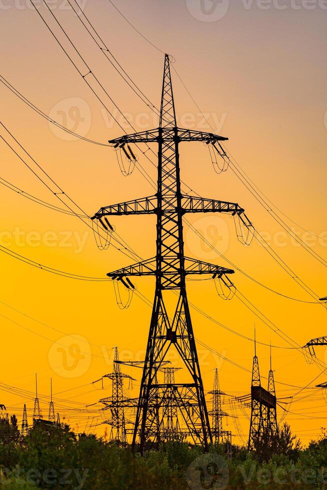 The silhouette of the evening electricity transmission pylon. Power line in the beautiful landscape of nature. Selective focus. photo