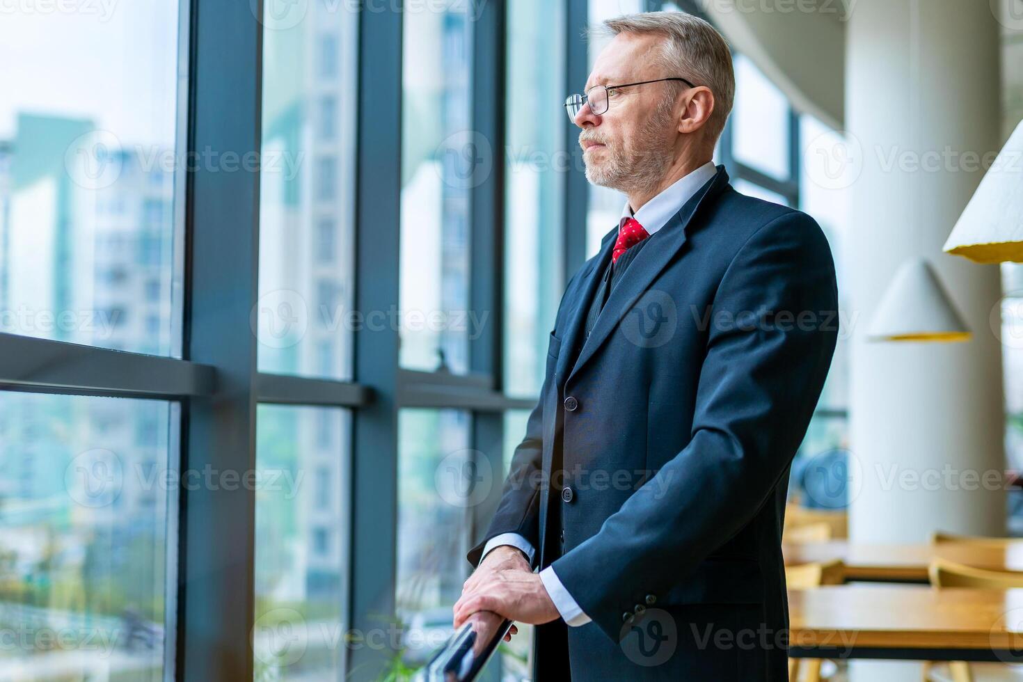 Man staying near big window. Businessman in suit thinking over ideas. Panoramic city view. Relaxing and taking break. photo