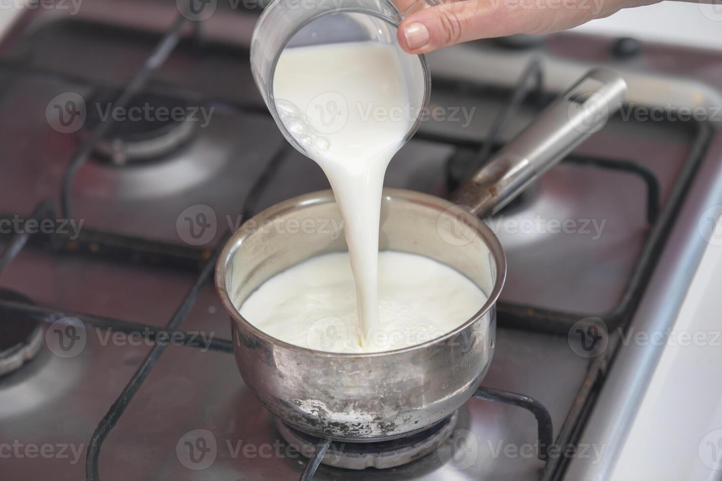 Boil milk in a small saucepan on the stove. Prepare milk porridge. photo
