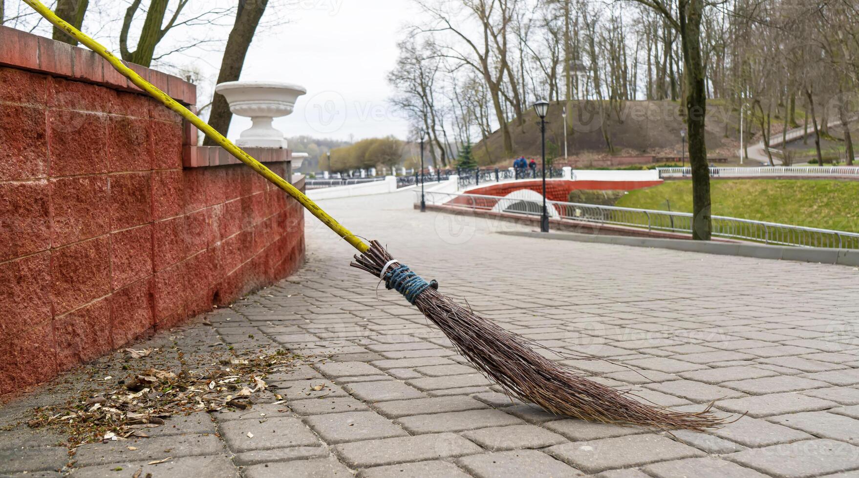 Retro broom made of dry branches against the backdrop of a city park. photo