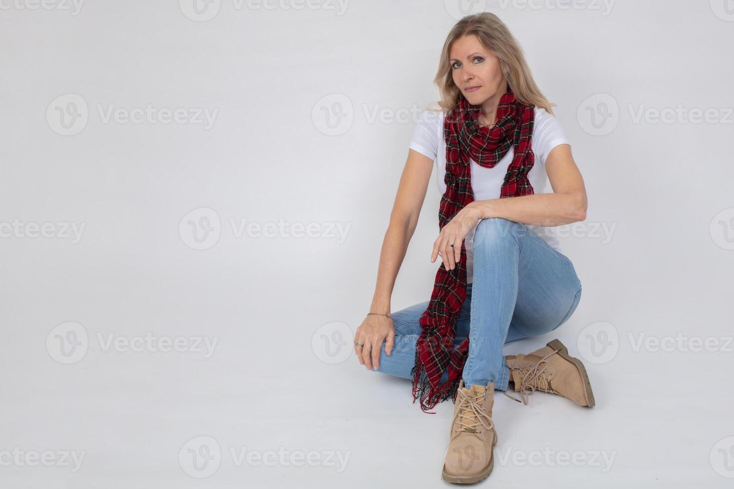 adulto hermosa esbelto mujer en pantalones y botas posando mientras sentado en el estudio. foto