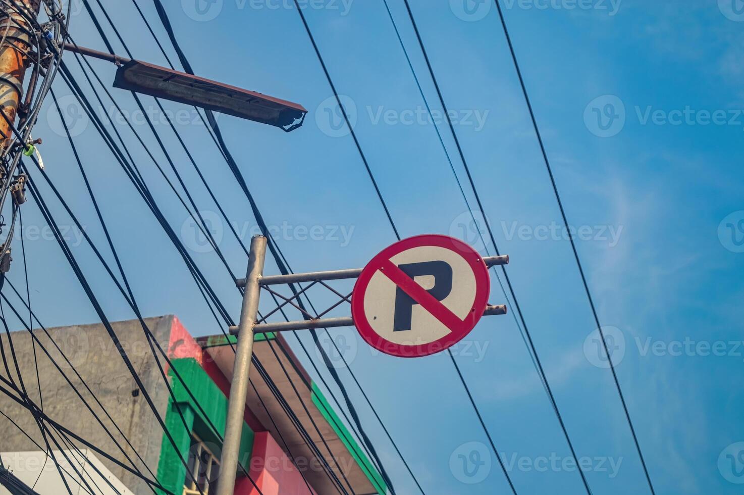 a no parking sign with messy wires in the background photo