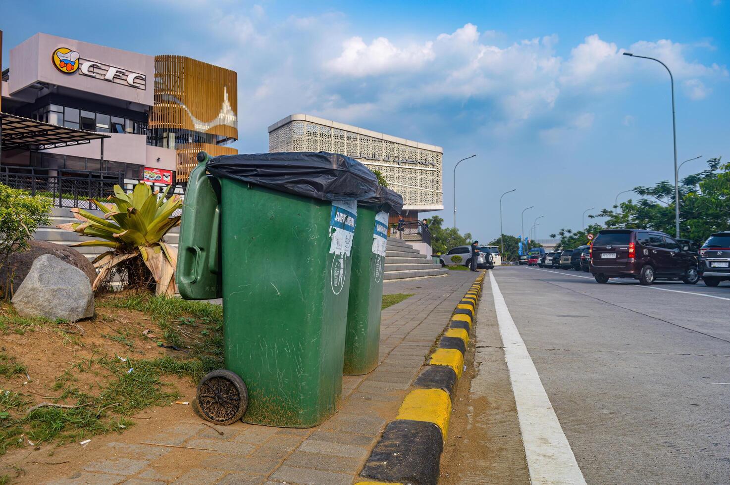 two green trash cans on the side of the parking lot in front of the rest area plaza on the Trans Java toll road, Indonesia, 23 December 2023. photo
